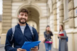 Studente sorridente con cartellina blu davanti all'università
