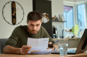 Uomo preoccupato controlla bollette al tavolo