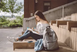 Ragazza scrive su quaderno seduta su gradini