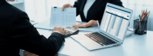 Professionisti analizzano documenti finanziari con laptop e calcolatrice