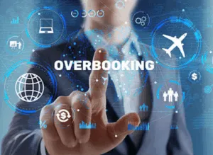 Manager tocca schermata digitale con scritta overbooking e icone viaggio