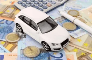 Modellino d’auto bianca su banconote e monete euro