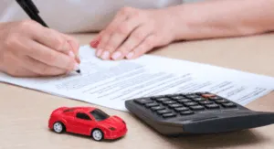 Firma di documenti auto con calcolatrice e modellino rosso
