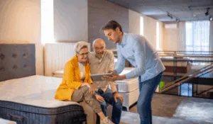 Venditore mostra tablet a coppia anziana in showroom